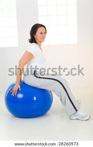 Elder woman dressed sportswear exercising with fitness ball.