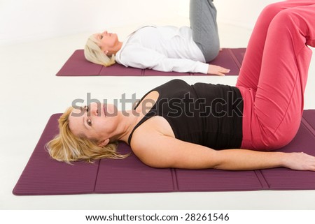 Two elder women during exercising on mat.