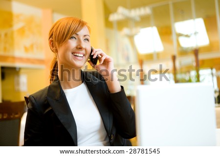 Young woman sitting in restaurant and speaking by cellphone.