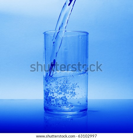 a glass of water flowing water, standing on the glass, on a blue background.