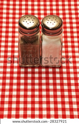 Salt and pepper shakers on red gingham tablecloth.