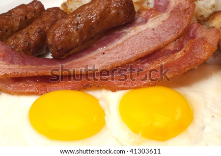 Breakfast plate with eggs sunny side up, bacon, and link sausage.