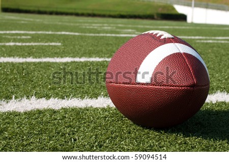 Closeup of American football on field with yard lines.