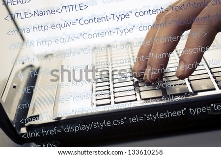 Finger press on laptop keyboard with computer source code
