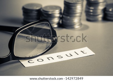 Financial consultant, eyeglasses and coins with paper of consult word