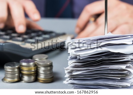 Bills in paper nail with hand calculating on background