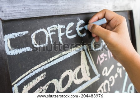 Hand writing information on blackboard in front of coffee shop, can be used as a small business starting concept