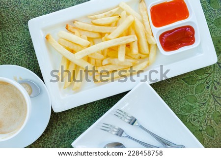 French fries on white plate with ketchup and chili paste sauce