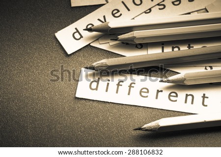 Closeup pieces of paper and pencil with Different word