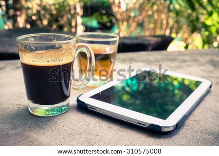 Black coffee with tea water and tablet on concrete table in the garden