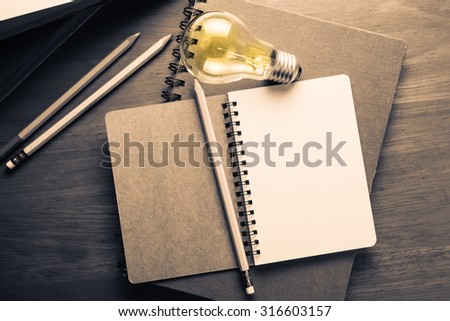 Opened spiral notebook with glowing light bulb on wood table