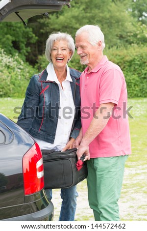 Senior couple with luggage at a black car