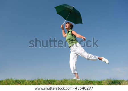Active senior woman with umbrella is jumping in front of blue sky