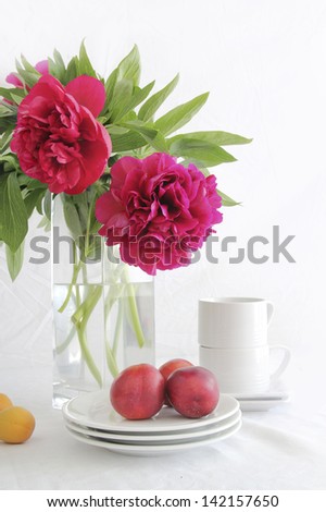 Bouquet of peonies with plates, cups, apricots and nectarines