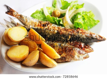 Grilled portugal sardine fish served with green salad and potatoes