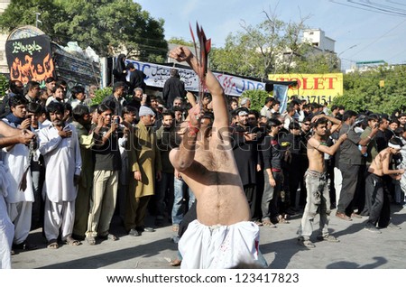 KARACHI, PAKISTAN - JAN 03: Shiite Muslims mourners scourging their bodies with knives swung in chain to show their devotion to Hazrat Imam Hussain (A.S) on January 03, 2013 in Karachi.