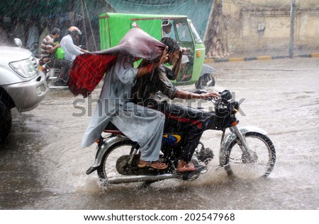 LAHORE, PAKISTAN - JUL 03: Commuters pass through stagnant rain water during heavy downpour of Monsoon Season at Shimla Hill road on July 03, 2014 in Lahore.