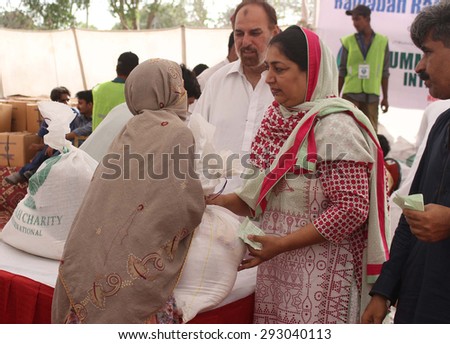 KARACHI, PAKISTAN - JUL 03: Members of Ummah Foundation are distributing ration  among needy people, at a welfare camp near PNS Shifa on July 03, 2015 in Karachi.