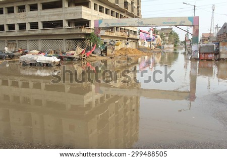 KARACHI, PAKISTAN - JUL 24: Commuters are passing through stagnant rain water near Korangi Crossing area on July 24, 2015 in Karachi. Commissioner ordered KMC to drain water from roads after rain,