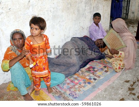 KARACHI, PAKISTAN, AUG 26: Flood affected women sit with their sick relative on floor at flood affectees relief camp established at a government school at Bhatiabad area on August 26, 2010 in Karachi, Pakistan