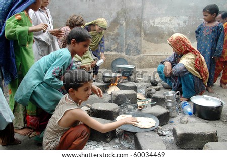 KARACHI, PAKISTAN - AUG 29: Flood affected children cook food at a flood relief camp on August 29, 2010 in Karachi.