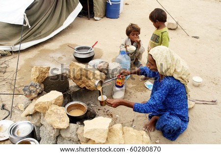KARACHI, PAKISTAN-AUG 31: Flood affected woman prepares tea for children at  flood relief camp established at Razzaqabad area in Karachi on Tuesday,  August 31, 2010.