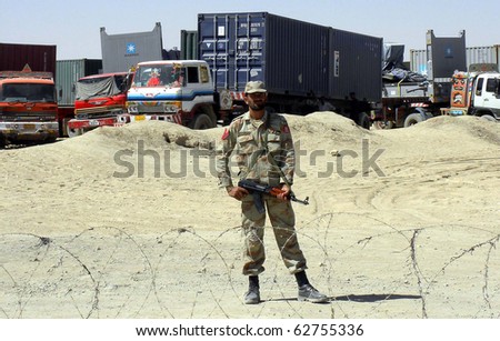 CHAMAN, PAKISTAN - OCT 07: Army official stands alert at terminal of Afghanistan-bound NATO trucks as security has been high alerted at terminal after incidents on NATO on October 07, 2010 in Chaman, Pakistan