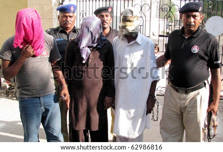 HYDERABAD, PAKISTAN - OCT 13: Police officials escort handcuffed kidnappers (face covered with cloths) during press conference at DPO office on October 13, 2010 in Hyderabad, Pakistan.