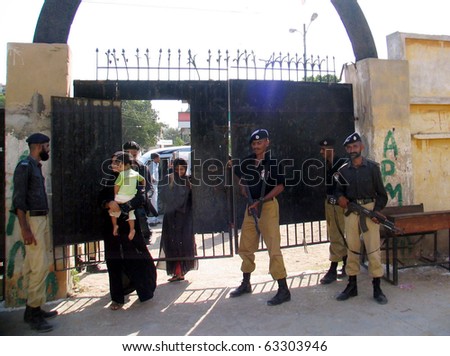 KARACHI, PAKISTAN - OCT 17: Police officials stand guard at a polling station at Orangi Town as security has been tightened during the by-election for PS-94, on October 17, 2010 in Karachi.