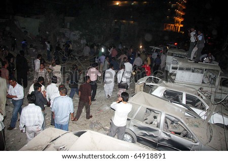 KARACHI, PAKISTAN - NOV 11: People gather near damaged vehicles which were destroyed in explosion, after explosion at the site  on November 11, 2010 in Karachi, Pakistan.