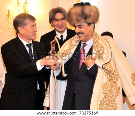 BISHKEK, KYRGYZSTAN - MAR 15: Kyrgyzstan Prime Minister, Almazbek Atambayev presents a traditional coat \'Kementay\' to Syed Yousuf Raza Gilani on occasion of a dinner on  March 15, 2011in Bishkek.