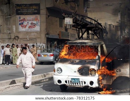 KARACHI, PAKISTAN - MAY 30: People look burning electric supply company (KESC) vehicle which was set ablaze by angry mob during a protest demonstration on May 30, 2011 in Karachi, Pakistan.