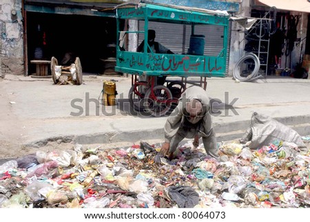 QUETTA, PAKISTAN - JUN 27: A man who collects garbage to earn his livelihood to support his family searches useful items at a heap of garbage that lays down at street on June 27, 2011in Quetta, Pakistan.