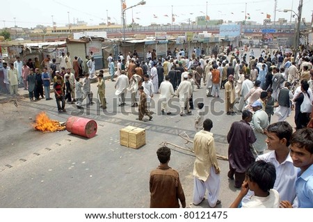 HYDERABAD, PAKISTAN - JUN 28: Angry protesters gather near burning wooden stuff at a road at Khawaja Ghareeb Nawaz Bridge as they are protesting against firing incident on June 28, 2011in Hyderabad, Pakistan.