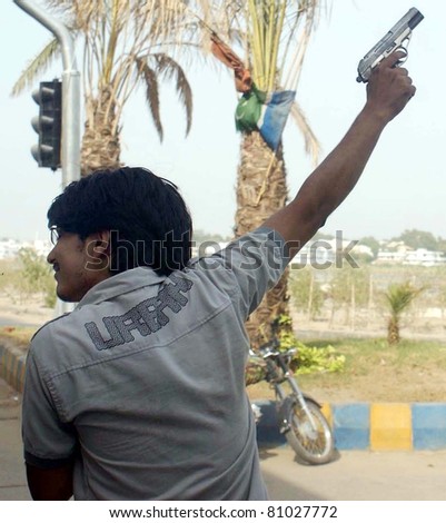 HYDERABAD, PAKISTAN - JUL 14: An armed unidentified youth fires his gun in air during a rally in favor of Peoples Party (PPP) Senior Leader, Dr.Zulfiqar Mirza on July 14, 2011 in Hyderabad, Pakistan.