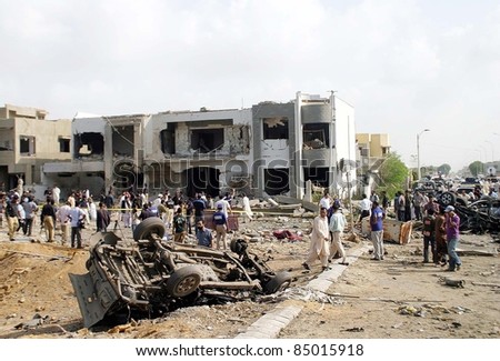 KARACHI, PAKISTAN - SEPT 19: Security officials gather at the site of explosion after suicide attack while a damaged building and wreckage of a vehicle on September 19, 2011 in Karachi, Pakistan.
