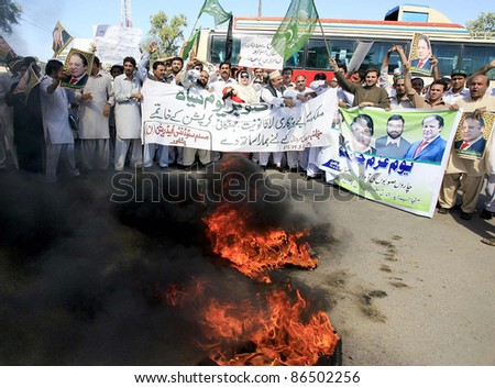 PESHAWAR, PAKISTAN - OCT 12: Supporters of Muslim League-N stand near burning tyres as they are protesting in favor of their demands in Peshawar, Pakistan on October 12, 2011.
