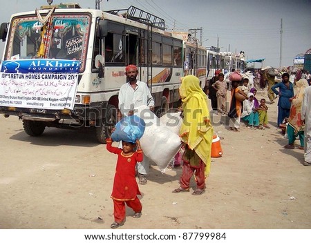 HYDERABAD, PAKISTAN - OCT 31: People, who were displaced and affected by recent rain and flood, with their bags gather near buses as they are going back to their areas October 31, 2011in Hyderabad Pakistan.