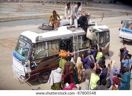 HYDERABAD, PAKISTAN - OCT 31: People, who were displaced and affected by recent rain and flood, load their bags on a bus as they are going back to their areas on October 31, 2011 in Hyderabad, Pakistan.