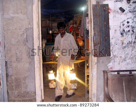 KARACHI, PAKISTAN - NOV 21: A shopkeeper carries lanterns on rent for his shop during electricity load-shedding in a main commercial market of city in Karachi on November 21, 2011.