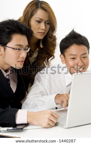 Three asian business people looking at a laptop computer