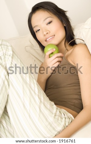 A pretty young asian woman in pyjamas with a green apple (shallow depth of field used)