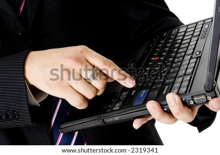 A young businessman in pin-striped suit about to hit the enter key on a laptop computer keyboard