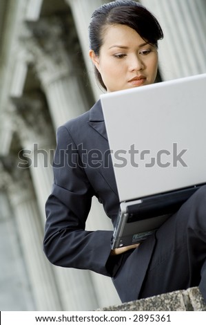 A businesswoman working on a laptop sat outside a grand old building