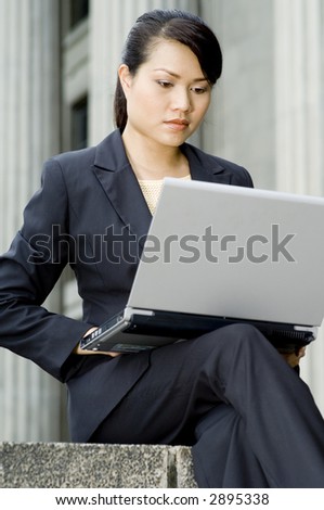A young attractive businesswoman with laptop working outside an old building