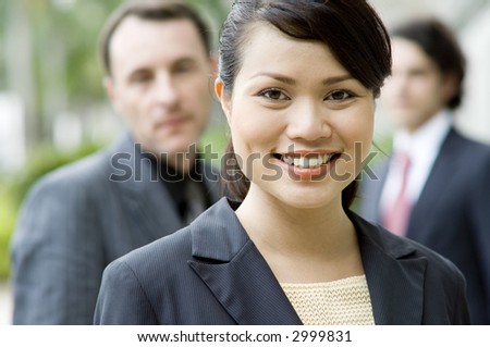 A young asian businesswoman standing in front of her team (shallow depth of field used)