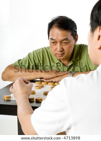 Two Chinese men in their fifties playing chess in the studio