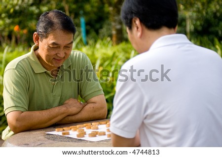 Two Chinese men in their fifties playing chess in the park