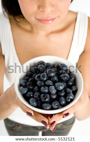 A wide angle shot of a bowl of blueberries being held by an attractive Asian woman