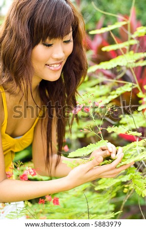 A beautiful young asian woman smelling a flower in the garden